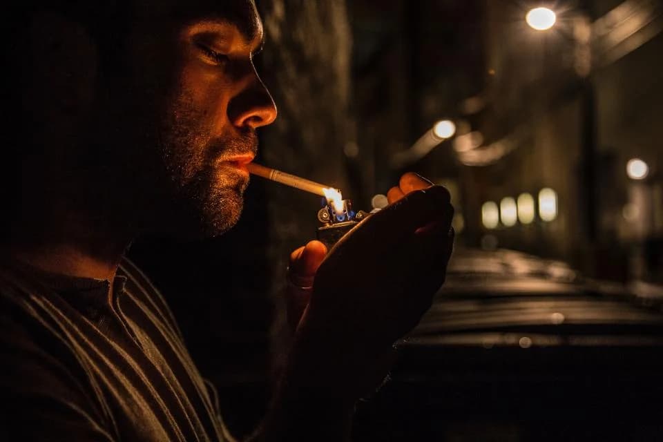 Bărbat care își aprinde o țigară, seara